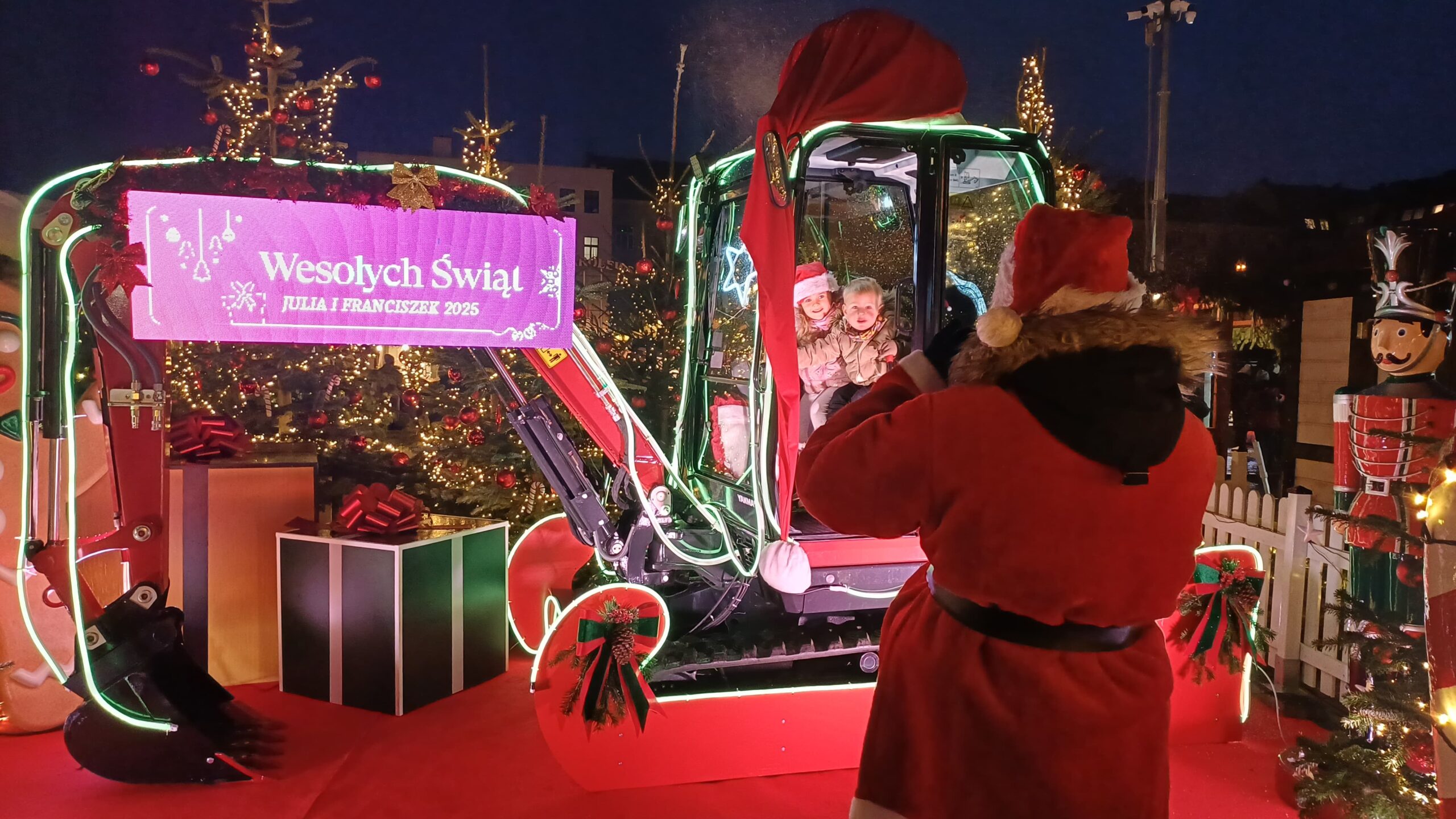 Święty Mikołaj przy minikoparce Yanmar SV26 – akcja promocyjna Grupy GPEC na Targu Węglowym.